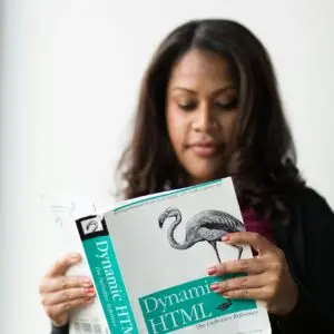 A woman focused on reading a book about Dynamic HTML indoors.
