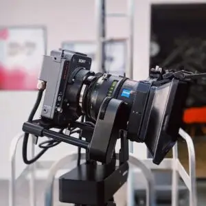 Side view of a professional video camera on a tripod outdoors, ideal for filming environments.